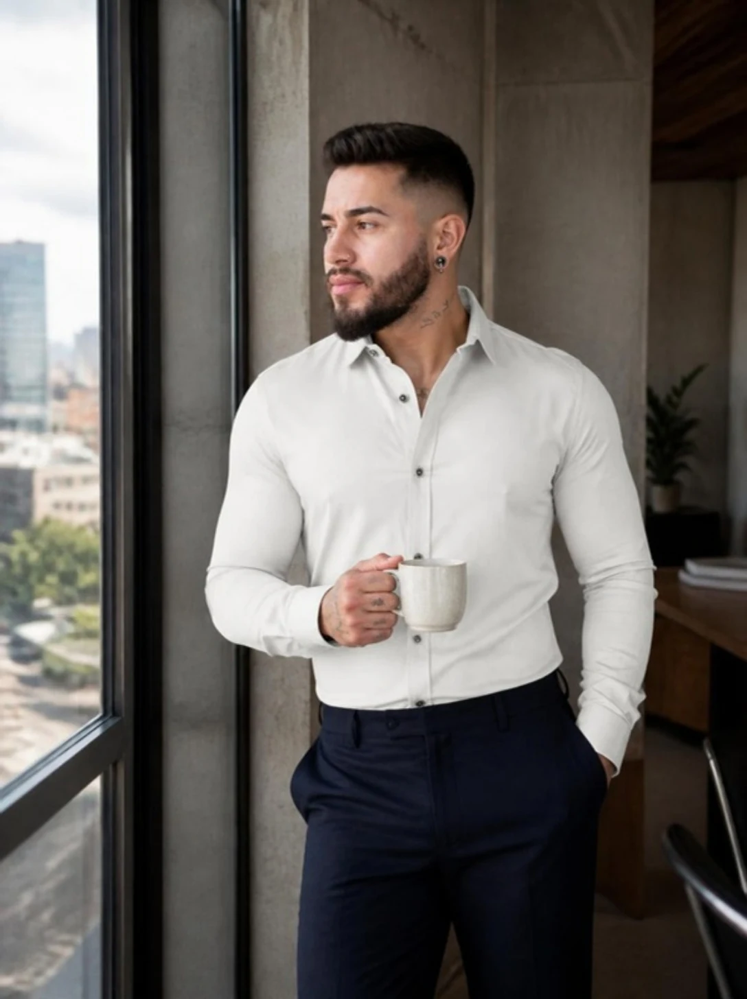 Camisa blanca por dentro de un pantalón azul, junto a la ventana de una oficina